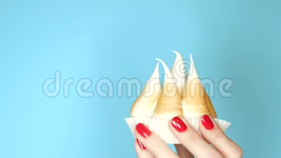 女性手上有指甲手里拿着一个蛋糕上面有奶油和炸薯条背景是蓝色的特写视频的预览图