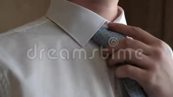 男人的手在白色衬衫上拉直蓝色领带早上一个男人打扮起来上班特写视频的预览图