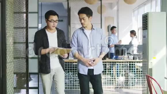 两位年轻的亚洲企业家在办公室讨论生意视频的预览图