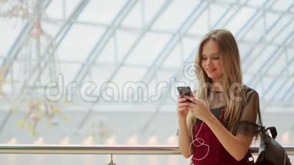 快乐的少女拿着包购物微笑着看着购物中心的电话收到好消息视频的预览图
