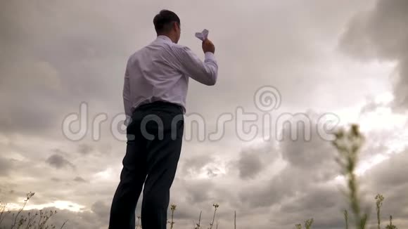 穿着白色衬衫的商人在乌云的背景下玩纸飞机慢动作视频的预览图