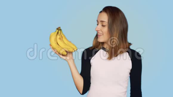 漂亮的微笑女人拿着一堆香蕉视频的预览图