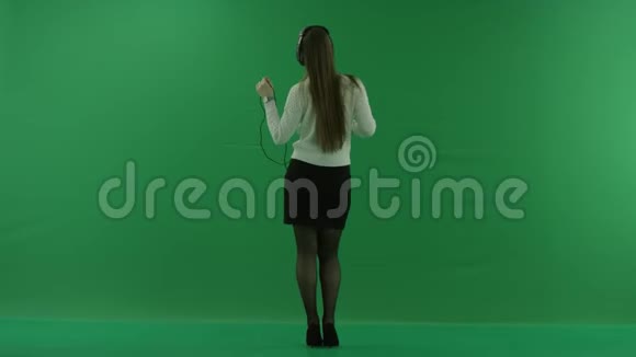 女孩站在镜头前戴着耳机在绿色屏幕上跳舞视频的预览图