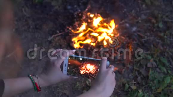这位女士用智能手机露营视频拍摄了明亮的篝火视频的预览图