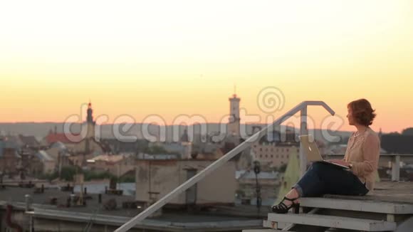 现代时尚的年轻女商人手提电脑与风景如画的欧洲城市景观背景日落视频的预览图