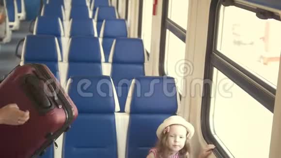 年轻漂亮的母亲带着女儿乘快车旅行把手提箱放在架子上视频的预览图