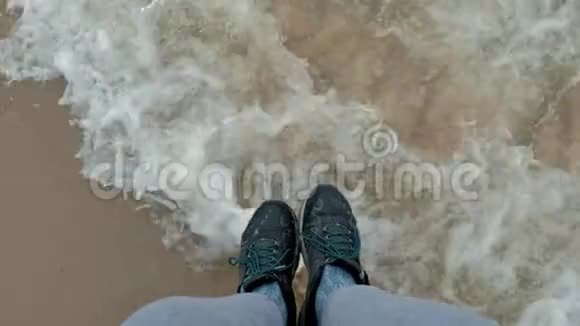 双脚穿着温暖的鞋子在海浪中暴风雨中视频的预览图