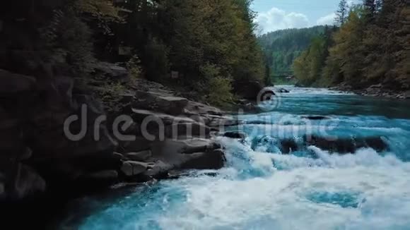 低速飞行过奔流的山河和瀑布蓝色在林间和山间日落视频的预览图