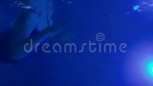 年轻孕妇夜间在游泳池游泳光照充足穿着蓝色泳衣做运动的女孩视频的预览图