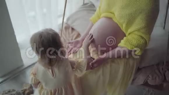 漂亮的孕妇和她的小女儿在房间里玩母亲得到了幸福因为她很快就会生育视频的预览图