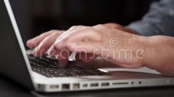 祖母在笔记本电脑后面工作用她那双带皱纹的旧手在键盘上打字现代退休老人从视频的预览图
