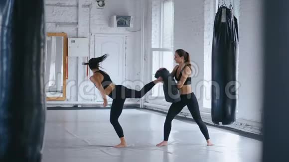 运动女性训练她的踢腿在她的持有的一个冲孔袋跆拳道或跆拳道的训练二视频的预览图