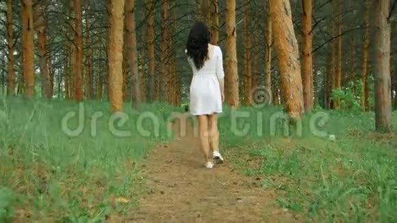 穿着白色短裤的年轻黑发女郎走在森林里的小径上视频的预览图