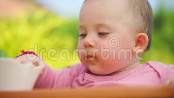 一个又小又有趣的孩子在露天吃妈妈勺子煮的粥视频的预览图