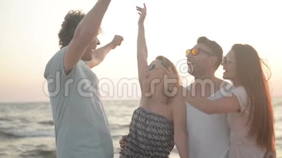 两个男人和他们惊人的女朋友微笑和拥抱在海边风天气的肖像视频的预览图