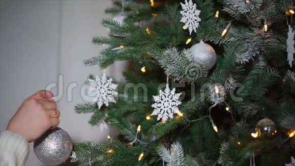 一个女人用节日的舞会装饰她家一棵圣诞树视频的预览图