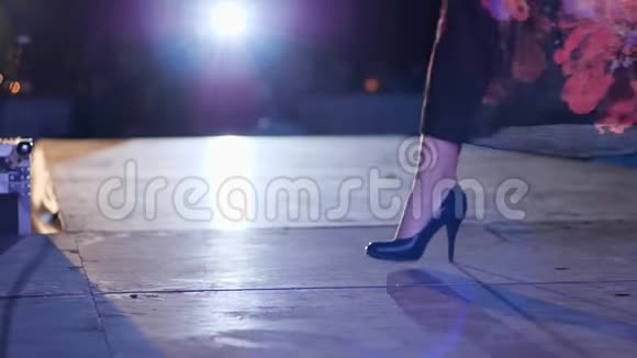 在泛光照明下腿型模特穿着时尚的高跟鞋沿着T台行走视频的预览图