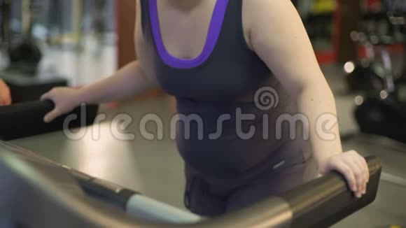 不健康的超重妇女在跑步机上锻炼慢慢地走着视频的预览图