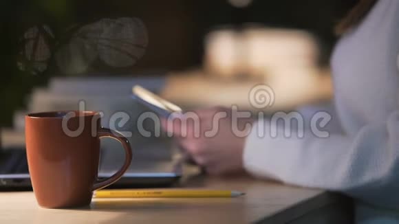 女士坐在咖啡店喝咖啡用手机上网视频的预览图