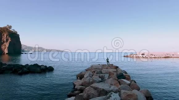 鸟瞰男子站在海滩上旅行概念文字空间带船海湾意大利山脉旅行概念视频的预览图