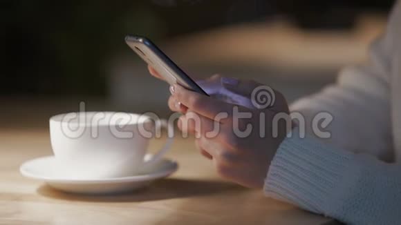 在舒适的咖啡屋里年轻女士在智能手机上滚动滑动页面视频的预览图