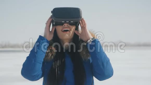 年轻女性在冬季使用VR耳机户外体验的肖像女孩用虚拟现实头盔视频的预览图
