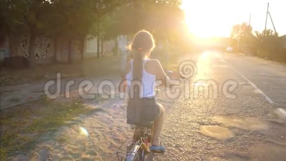 女孩骑着自行车在街上骑着车慢动作视频的预览图