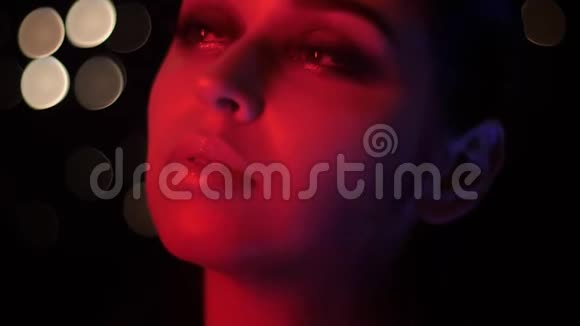 特写镜头漂亮的女性脸与惊人的时尚化妆与红色霓虹灯和bokeh背景摆在前面视频的预览图