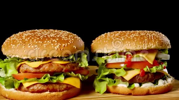 特写两个开胃汉堡与芝麻包子旋转的黑色背景快餐无缝循环镜头视频的预览图