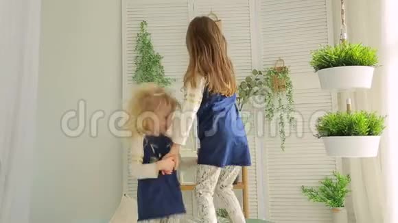 在明亮的房间里两个小女孩在床上跳着绿色的植物视频的预览图