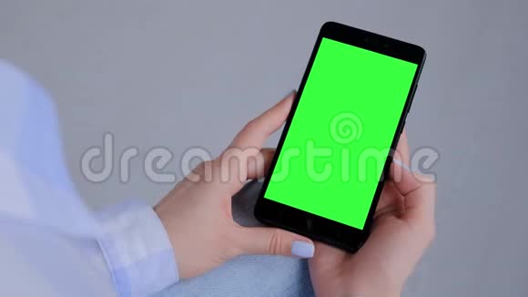 女人拿着黑色智能手机空白的绿色屏幕共用空间概念视频的预览图