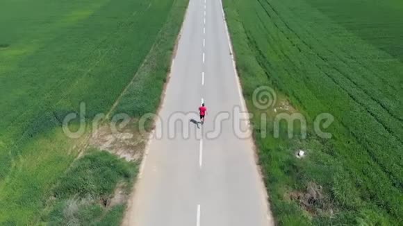 空中慢动作无人机跟踪男子独自在乡村道路上跑步穿越耕地户外活动健身我们视频的预览图