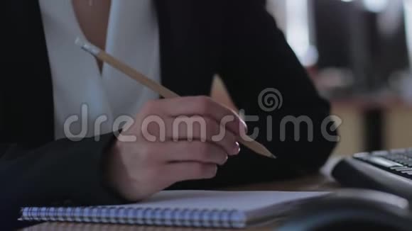 办公室工作人员拿着铅笔一边拿着笔记本和电脑坐在办公室的办公桌前视频的预览图
