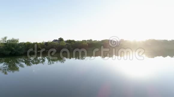 黎明时美丽的风景湖明亮的阳光下绿树之间洁净的湖视频的预览图