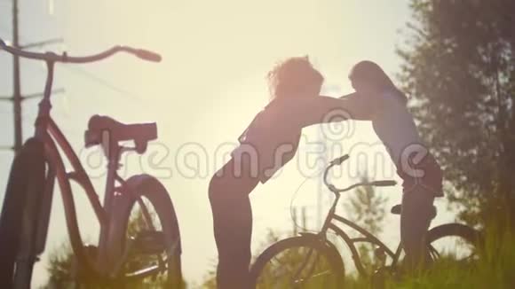 女孩们骑自行车的人互相照顾在帕克家取暖在她们的自行车旁边夏日的晴天视频的预览图