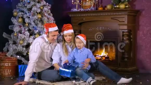 幸福的家庭在圣诞壁炉附近打开圣诞礼物视频的预览图