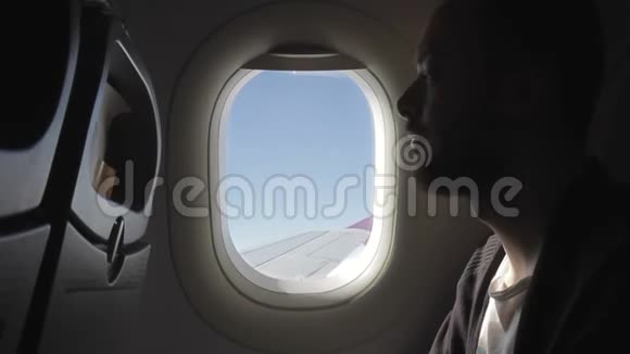 年轻人坐在飞机上沉思地看着窗外视频的预览图