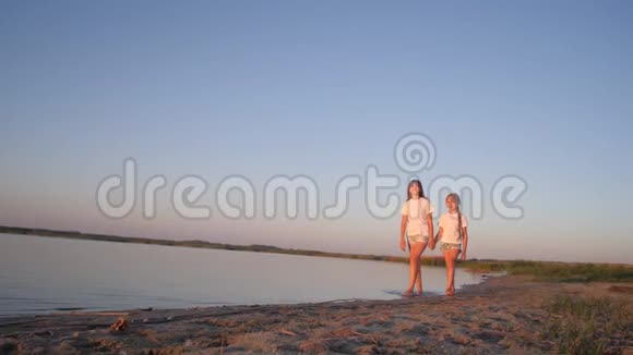 女孩青少年沿着海滩散步微笑视频的预览图