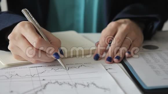 女员工用钢笔在办公室的桌子上做笔记视频的预览图