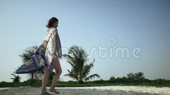 美丽的女孩穿着紧身裙在海滩上散步视频的预览图