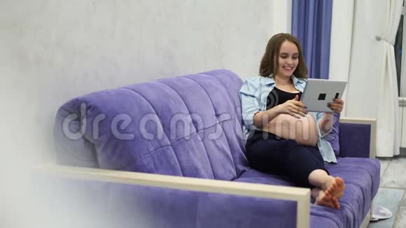 一位孕妇通过视频与她的朋友通过互联网使用触摸平板电脑进行交流视频会议视频的预览图