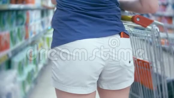 超市里的一个女人正从柜台边经过篮子4K特写一个穿白色短裤和一个红色的女人视频的预览图