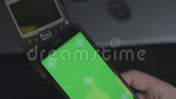 顶部的人使用非接触式支付与智能手机手机上的绿色屏幕模板视频的预览图