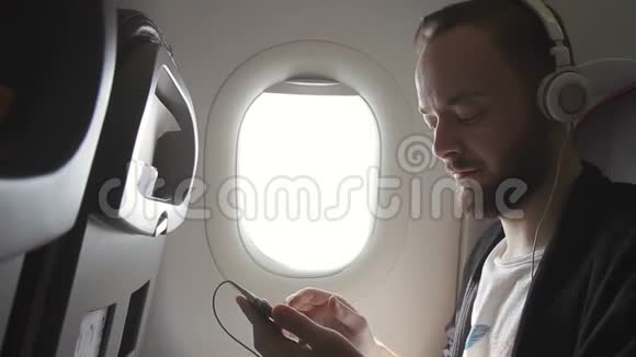 飞机上的人戴着耳机点击智能手机的屏幕视频的预览图