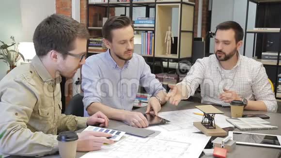 三位专家讨论商务问题坐在办公室使用平板电脑视频的预览图