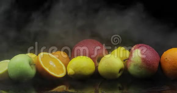 热带柠檬橘子苹果在寒冷的冰云中雾在黑暗的背景上冒烟视频的预览图