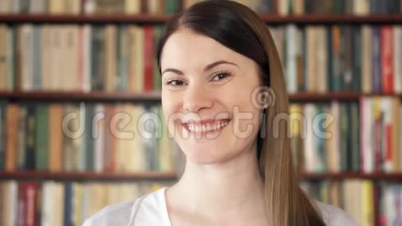 女大学生在图书馆微笑上学的第一天背景书架视频的预览图