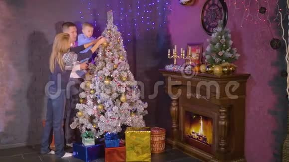 年轻快乐的家庭母亲父子一起装饰圣诞节和新年树视频的预览图