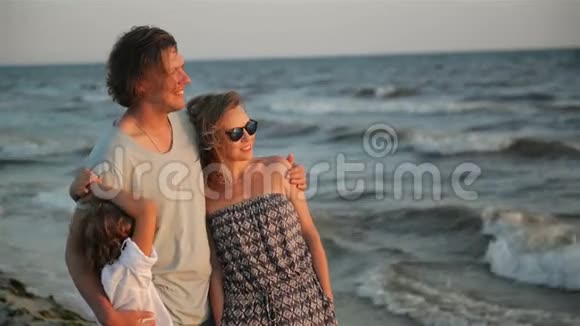 日落时分英俊的父亲和迷人的母亲和儿子一起在海边度过时光的肖像视频的预览图