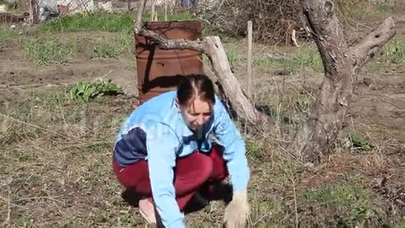 一个女人在花园里工作把草从地上移走视频的预览图